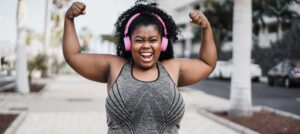 A Black woman in sports clothing and a sports bra pumps her arms during a run