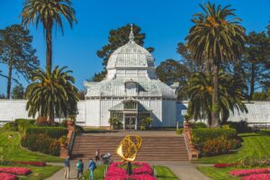 Conservatory of Flowers in Golden Gate Park with pink flowers in front of the Victorian building