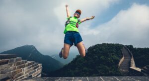 A woman celebrates her run on the Great Wall of China, one of the running destinations.